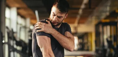 En mann holder seg til skulderen