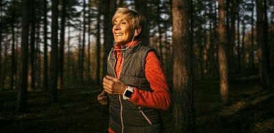 En dame er på joggetur i skogen. Foto