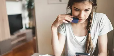 En dame sitter ved et bord og ser på telefonen sin. Foto