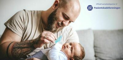 En mann gir en smukk til en baby. Foto