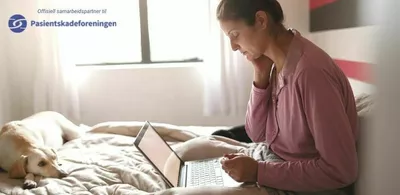 En dame sitter i en seng med en laptop. Foto
