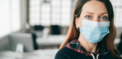 En dame med maske ser i kamera. Foto