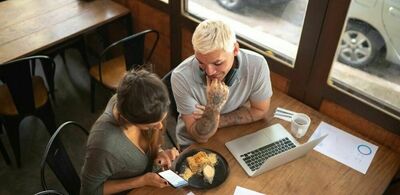 En mann og en dame sitter ved siden av hverandre på et bord inne på en cafe. Foto