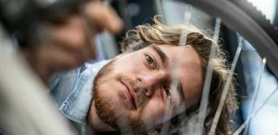 En mann skrur på et sykkelhjul. Foto