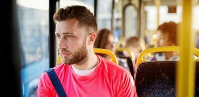 En mann sitter på bussen og ser ut vinduet. Foto