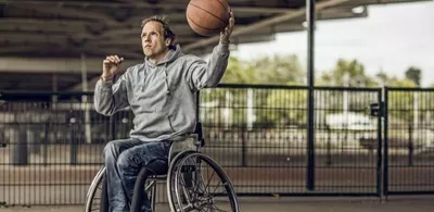 En mann i rullestol spiller basketball